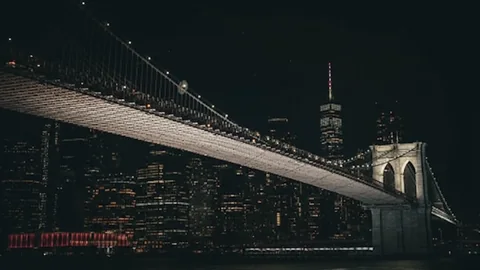 New York Brooklyn Bridge. The illuminated Brooklyn Bridge spans the night skyline of New York. The dark city scene adds depth to modern workspaces.